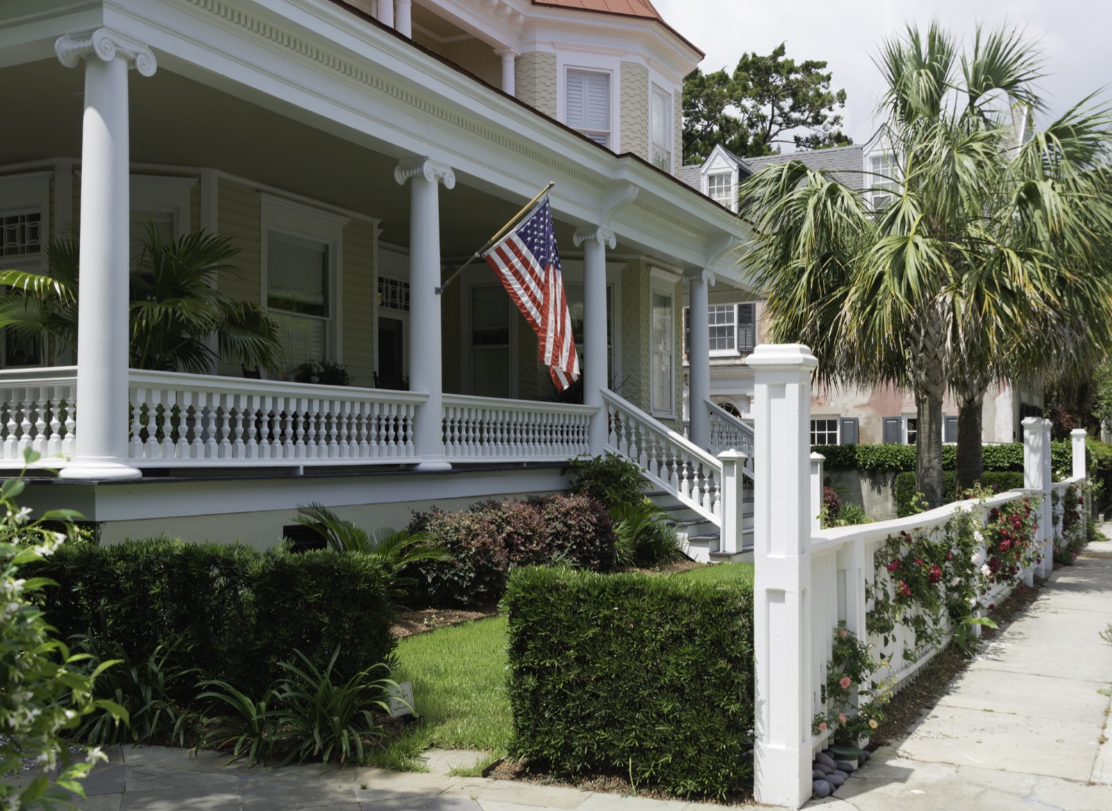 A historic coastal home with a columned front porch and palmettos.