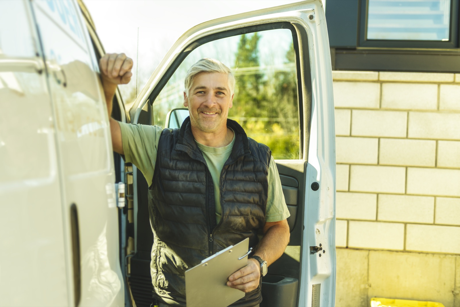 A trades operator with a clipboard starting his day at his service van.